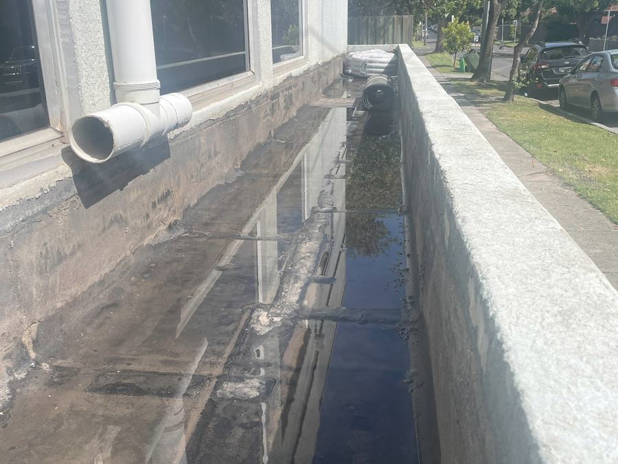 Water ponding against windows in a failed façade planter trough