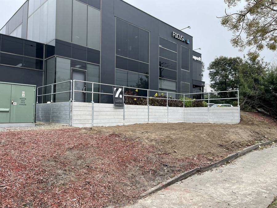 Completed concrete sleeper retaining wall with safety handrail at a Moorabbin commercial property