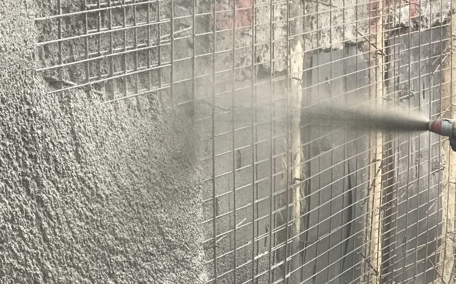 Shotcrete being sprayed onto reinforcement mesh during structural retention works